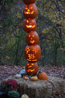 A tower of carved pumpkins being lit up by candles